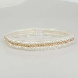Detailed view of woven hairband with white pearls and gold metal chain embellishments