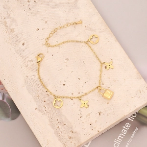Detalle de pulsera dorada con dijes de estrellas y candado grabado de estilo chic