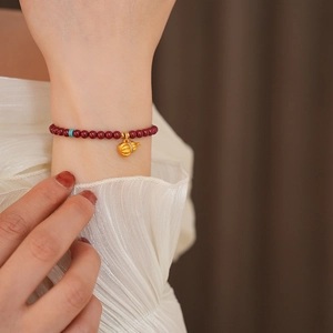 Detail of cinnabar beaded bracelet with gold gourd pendant and crystal accents