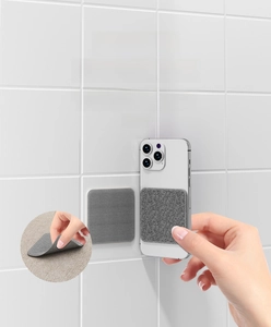 Detail view of gray square adhesive non-slip pad for sofa cushions on white tile wall