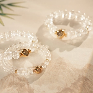 Macro detail of clear crystal beaded bracelets with golden clover charms and metal spacers