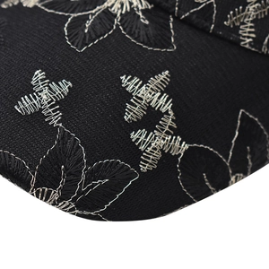 Macro detail of exquisite floral embroidery and silver thread on black twill baseball cap