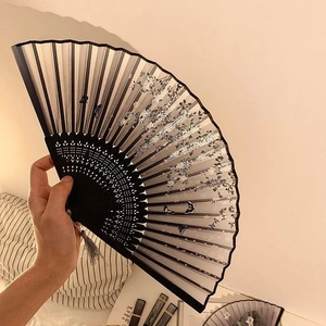 Detail of a vintage black folding fan with butterfly prints and elegant grey tassel