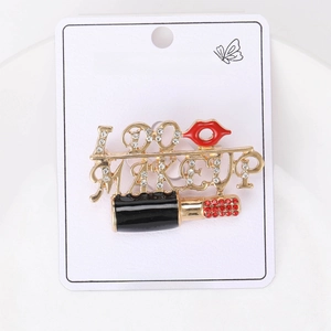 Macro detail of 'I DO MAKEUP' brooch with red crystals and gold lipstick design