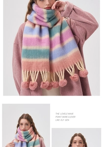 Close-up detail of a colorful striped scarf with plush pom-poms and fringe tassels
