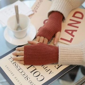 Detail of brick red cable knit fingerless gloves showing soft ribbed texture and warm style
