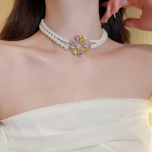 Detail einer zweireihigen Perlenkette mit Blumenanhänger und bunten Kristallen