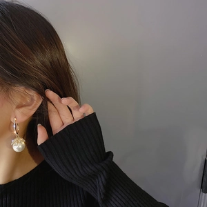 Detail view of elegant gold C-shaped earring with pearl and cubic zirconia on a model