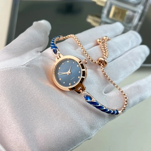Detailed macro of rose gold quartz watch featuring navy enamel and crystal hour markers