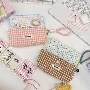 Detailed view of checkered quilted pencil cases with polka dot lining and button closure