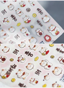 Détail des stickers 3D Maneki Neko pour ongles avec pièces d'or et motifs de chat porte-bonheur