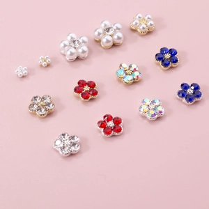 Macro detail of colorful five-petal nail charms with pearls and rhinestones on pink base