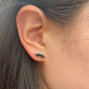 Black matte moustache stud earring worn on model ear for a minimalist unisex look
