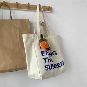Detail of off-white canvas tote bag with Enjoy The Summer print and orange charm