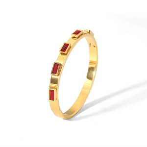 Detailed macro view of gold-plated stainless steel bangle with inlaid red rectangular crystals