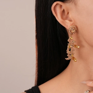 Golden Chinese 'Fa' character drop earrings with sparkling rhinestones on model