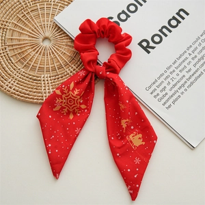 Detail of red Christmas scrunchie with long ribbon, gold snowflake and reindeer patterns