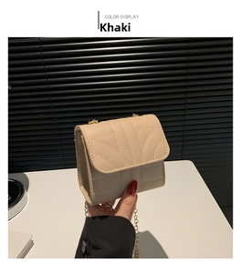 Close-up of khaki quilted square bag with gold chain strap held by a model