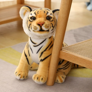 Realistic sitting tiger plush toy with orange stripes and bright brown eyes on wooden table