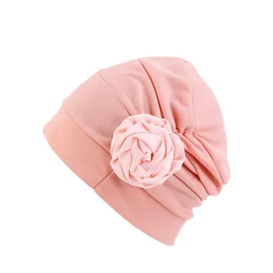 Gros plan d'un turban rose avec texture de tissu plissé et détail de fleur de rose