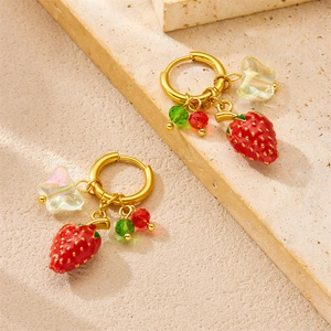 Fashionable strawberry and butterfly bead earrings on a beige stone surface