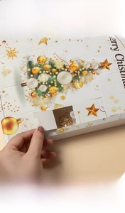 Detail of opening a 24-day Christmas advent calendar box with golden jewelry gifts