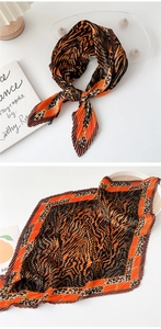 Detail of pleated silk scarf with orange and brown animal print shown tied and flat