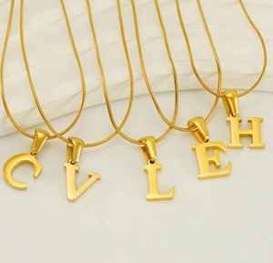 Detail of gold snake chain necklaces with polished 26 initial pendants C V L E H