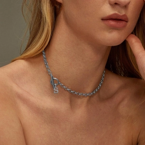 Close-up of a silver-toned chain necklace with an S-letter pendant worn by a model
