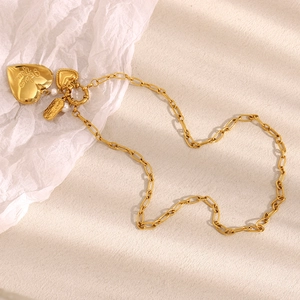 Detail of 18K gold-plated heart and pearl charms on a stylish paperclip chain necklace
