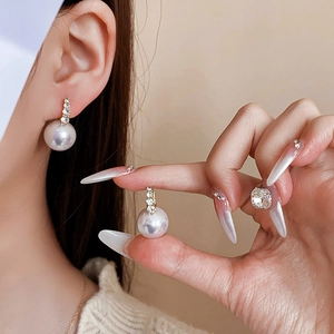Detail of luxury pearl earrings with sparkling rhinestones worn on a model's ear