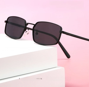 Detail of retro small rectangle sunglasses with thin black metal frame on pink background