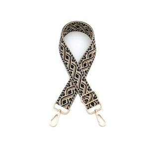 Détail de la bandoulière tissée aux motifs géométriques et boucles métalliques dorées