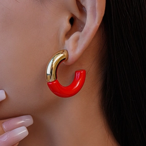 Close-up of gold and red acrylic C-shaped earring worn on model's ear, sleek design