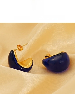 Detail of C-shaped 18K gold-plated earring with translucent deep blue resin on silk