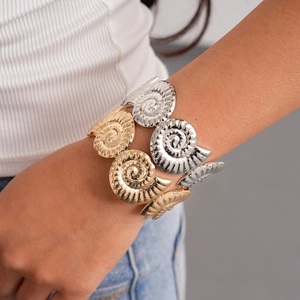Detail of gold and silver nautilus shell spiral bangles worn on a wrist for a modern look