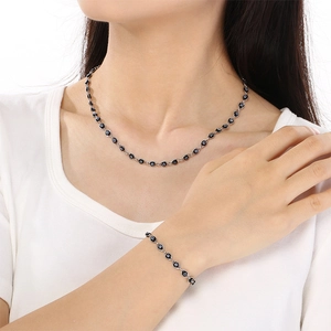 Detail shot of silver necklace and bracelet set featuring blue and black evil eye beads