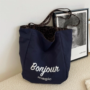 Close-up of navy tote bag with Bonjour magic print and leopard print lining detail