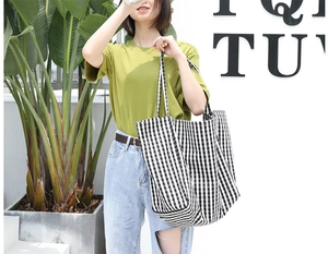 Detail of large black and white checkered canvas tote bag worn by model in natural light