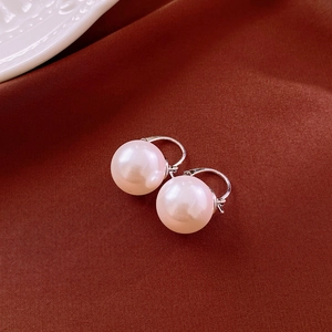 Détail macro de boucles d'oreilles perles roses sur fond de soie marron luxueux