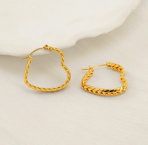 Detail of gold heart earrings showing textured braided pattern and hinge closure