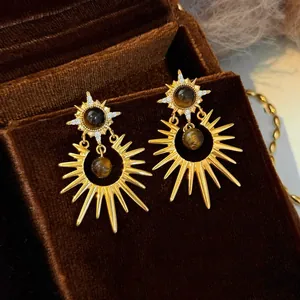Detailed view of vintage gold sunburst earrings with tiger eye beads in a velvet box