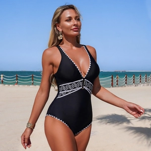Detail of a black one-piece swimsuit featuring a deep V-neck and white woven edges