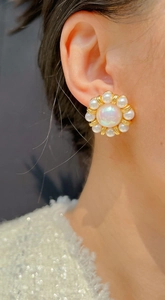 Close-up of flower stud earring with large pearl center and small white pearls on ear