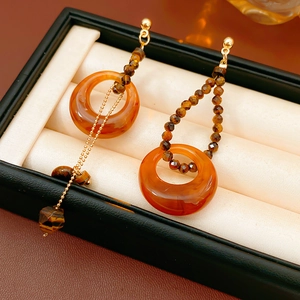 Detailed macro view of asymmetric vintage earrings with amber resin and tiger eye stones