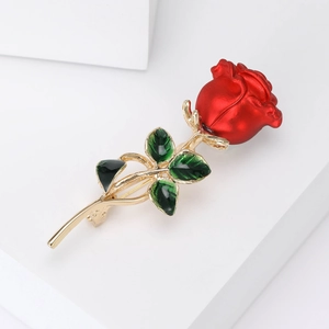 Macro shot of elegant red rose brooch with green enamel leaves and golden metal stem