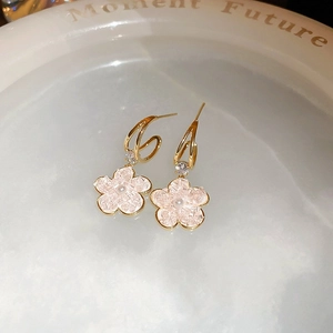 Detailed shot of gold-plated flower earrings with pink crystal petals and pearl accents