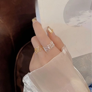 Close-up of gold and silver hollow flower rings with zircons worn on hand while reading