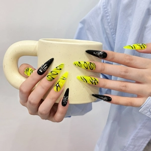 Handmade punk style press-on nails with yellow and black tiger patterns and 3D silver charms