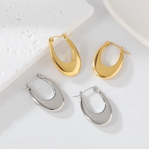 Polished gold and silver U-shaped metal earrings on a minimalist white stone setting